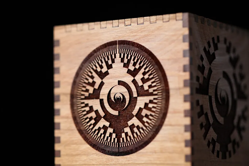Close-up of a cherry wood box with a deeply engraved circular pattern on the face and laser-cut finger joints at the corner