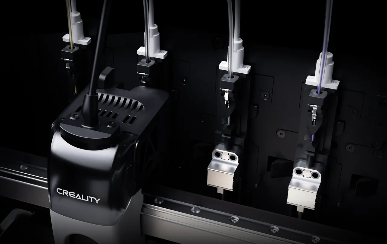 Close-up of the KliTek system in Creality's render: two spare hotends with silver heater blocks hang on the rail, each with its own filament tube, while the black Creality toolhead on the left carries the hotend in use
