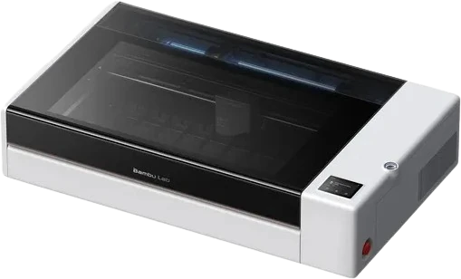 The Bambu Lab R1 CO2 laser cutter seen from the front right: a wide white body with a dark tinted lid over the full 600 by 300 mm bed, a touchscreen on the right-hand side and a red emergency stop button on the front corner