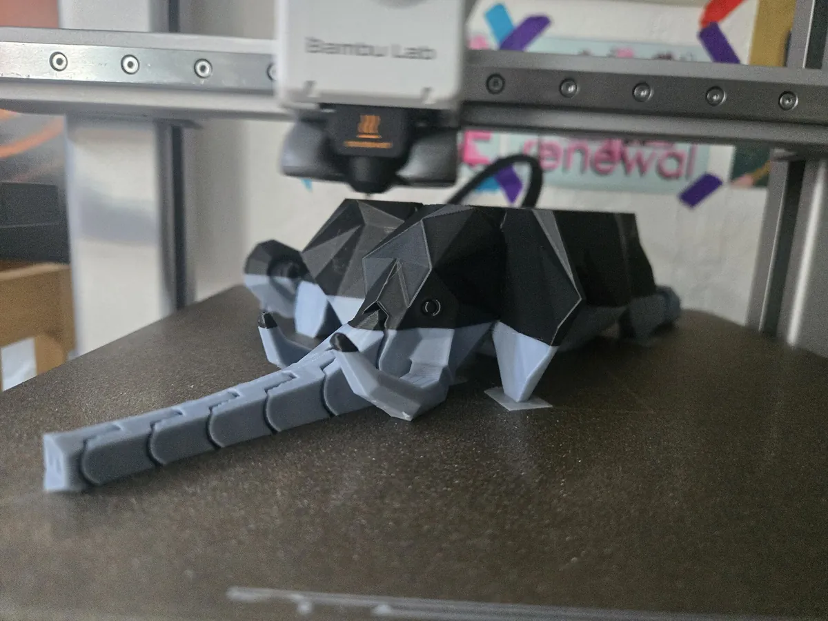 A finished low-poly elephant in grey and black on the build plate of the same Bambu Lab A1